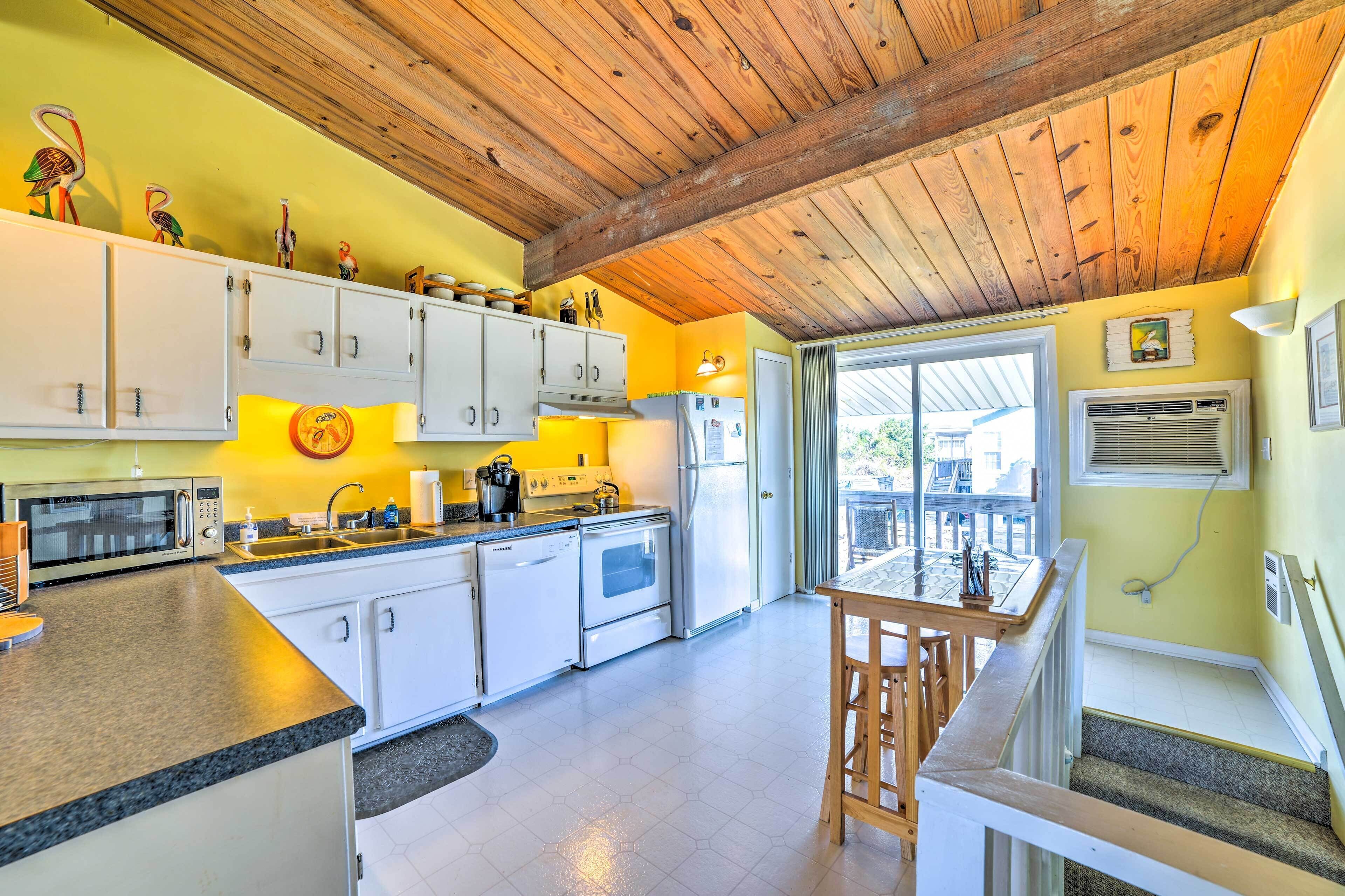 A kitchen with white cabinets, a microwave, stove, and a sink.
