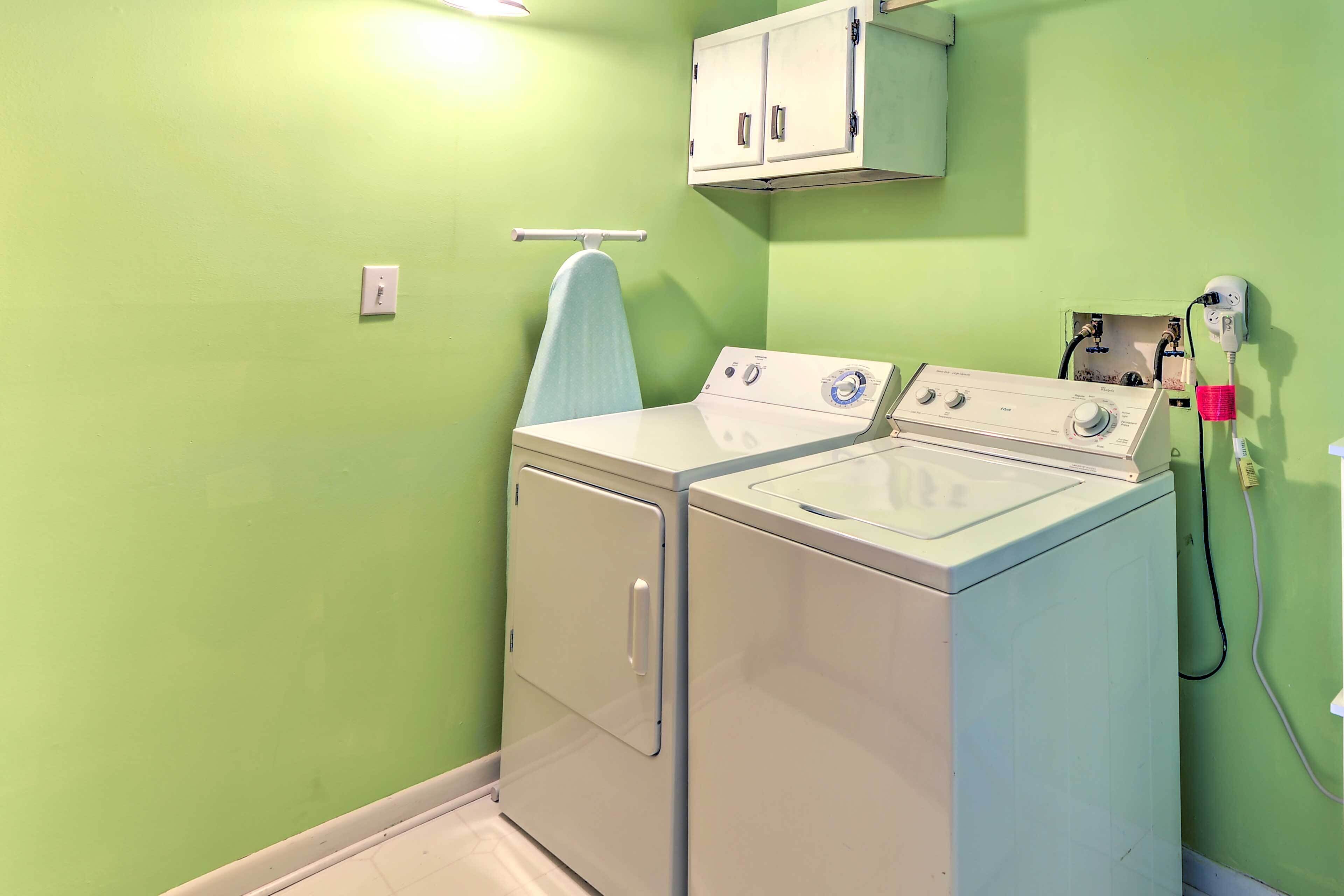 A laundry room with two white washers and dryers, a towel rack, and a cabinet above the dryers.