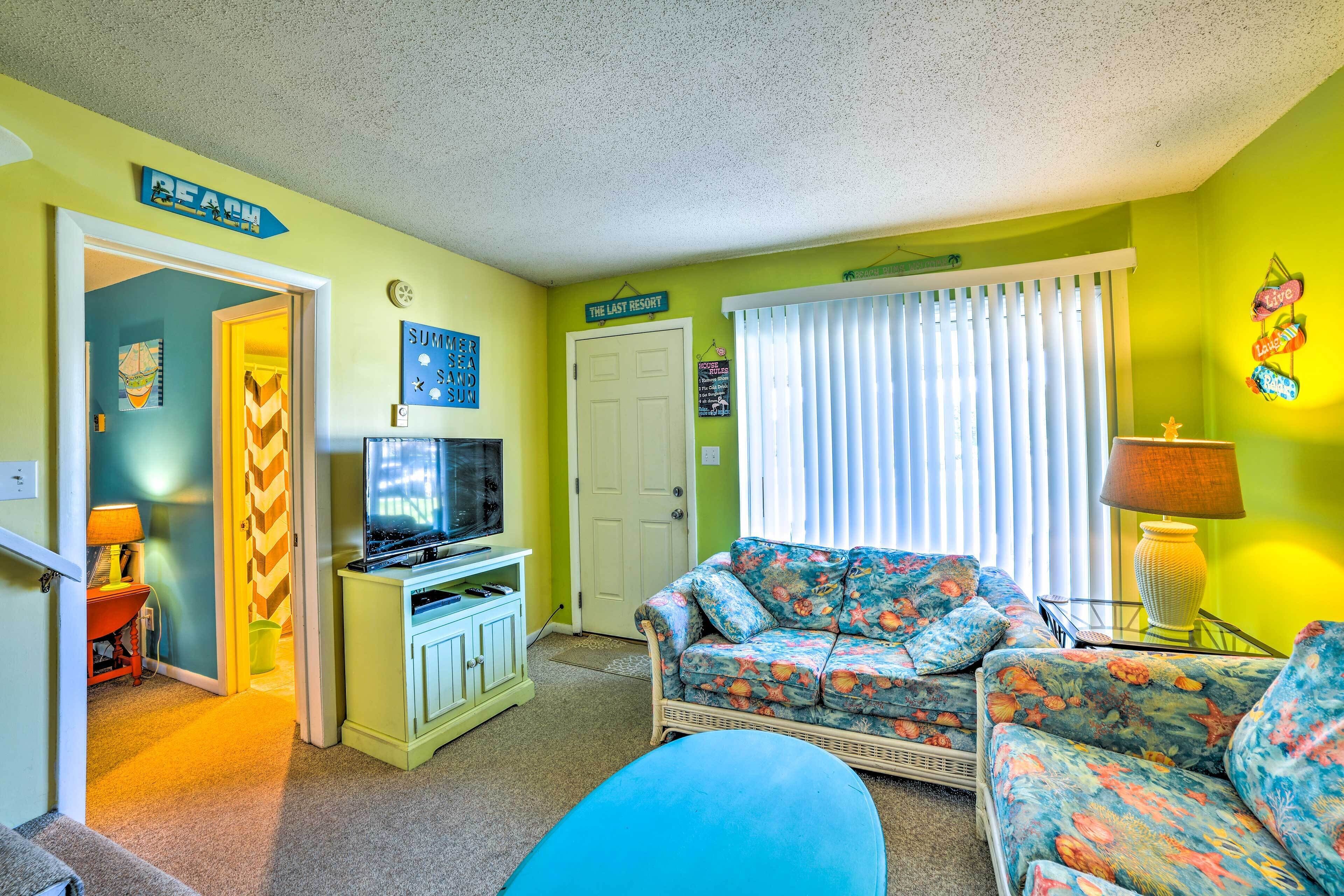 Una sala de estar con televisor, un sofá y una silla. Hay una puerta con la leyenda 'The Last Resort' y un cartel que dice 'Beach'.
