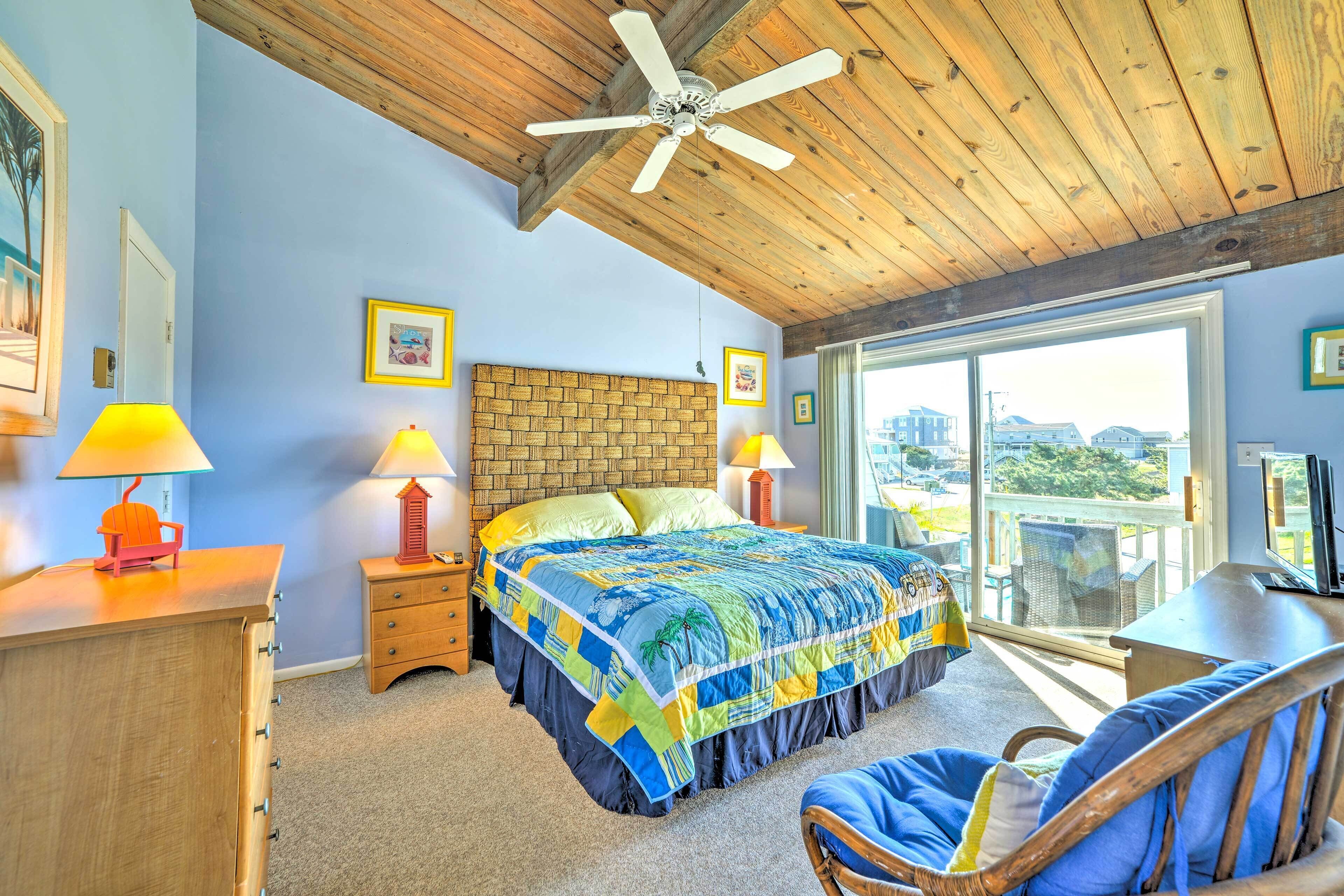 A bedroom with a bed, wooden ceiling, and a view through a large window.