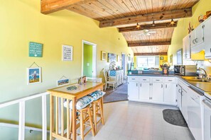 A kitchen with white cabinets, a wooden ceiling, and a dining area with a table and chairs. - Coastal Atlantic Beach Duplex < 1 Mi to Boardwalk! (Atlantic Beach)