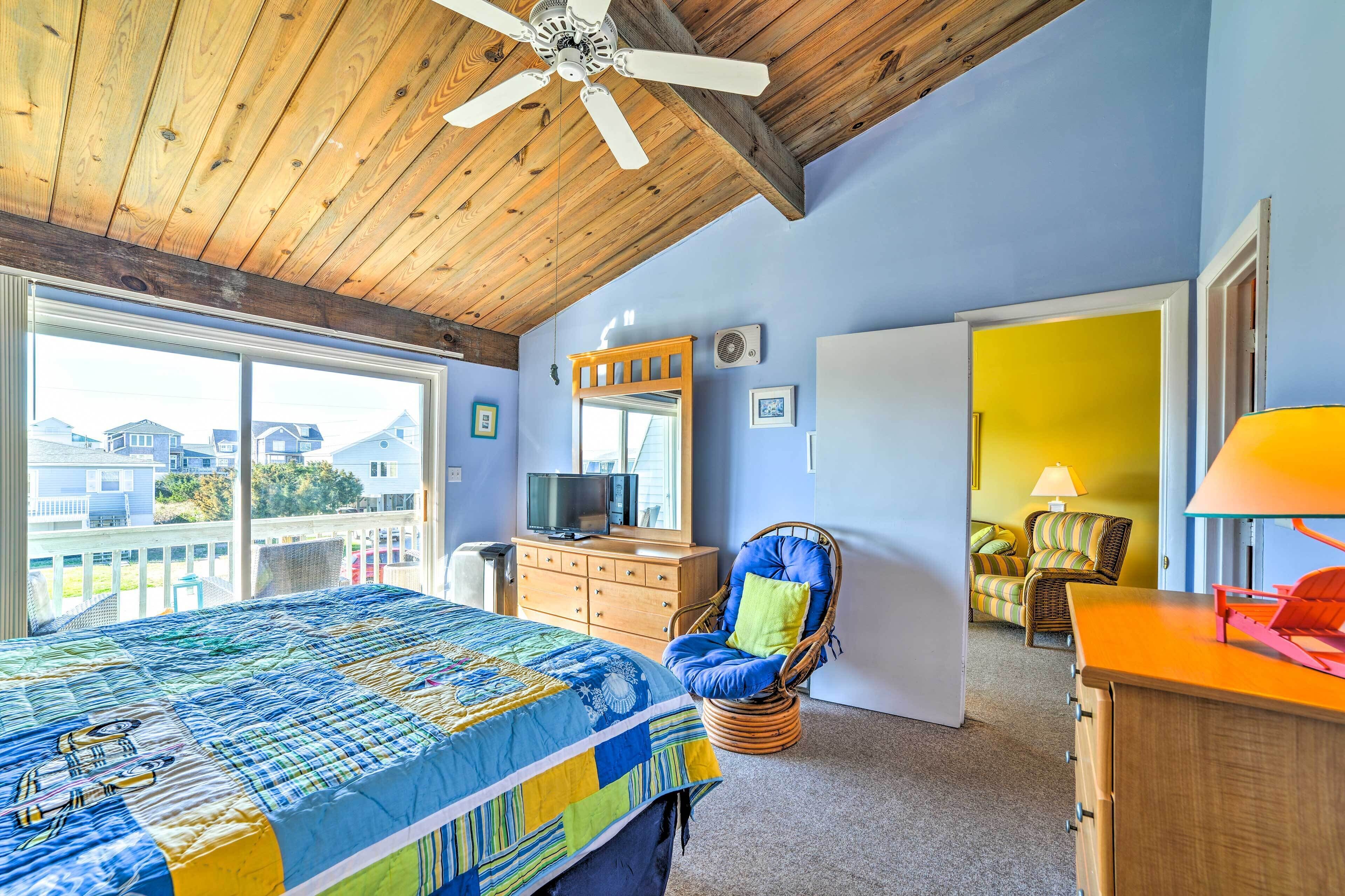 A bedroom with a large bed, a ceiling fan, a dresser, and a chair.