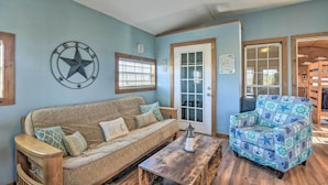 Una habitación con una pared azul, un adorno en forma de estrella, una puerta de madera, un sillón azul con estampado y una mesa de centro de madera.