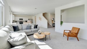 A modern living room with a sofa, coffee table, and chair. There is a kitchen in the background with a microwave and cabinets. - Near Empire Polo Field: Coachella Vacation Rental (Coachella)