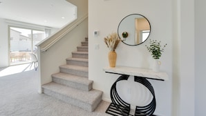 A modern interior with a staircase, a marble console table, a round mirror, and a potted plant. - Near Empire Polo Field: Coachella Vacation Rental (Coachella)