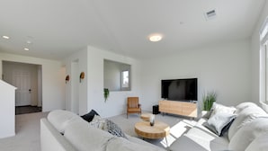 A modern living room with a large sofa, a wooden coffee table, a TV, and a plant. - Near Empire Polo Field: Coachella Vacation Rental (Coachella)