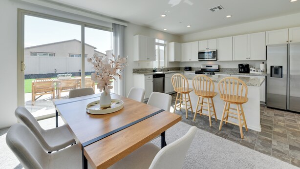 A modern kitchen with white cabinets, stainless steel appliances, and a dining area with a wooden table and chairs. - Near Empire Polo Field: Coachella Vacation Rental (Coachella)