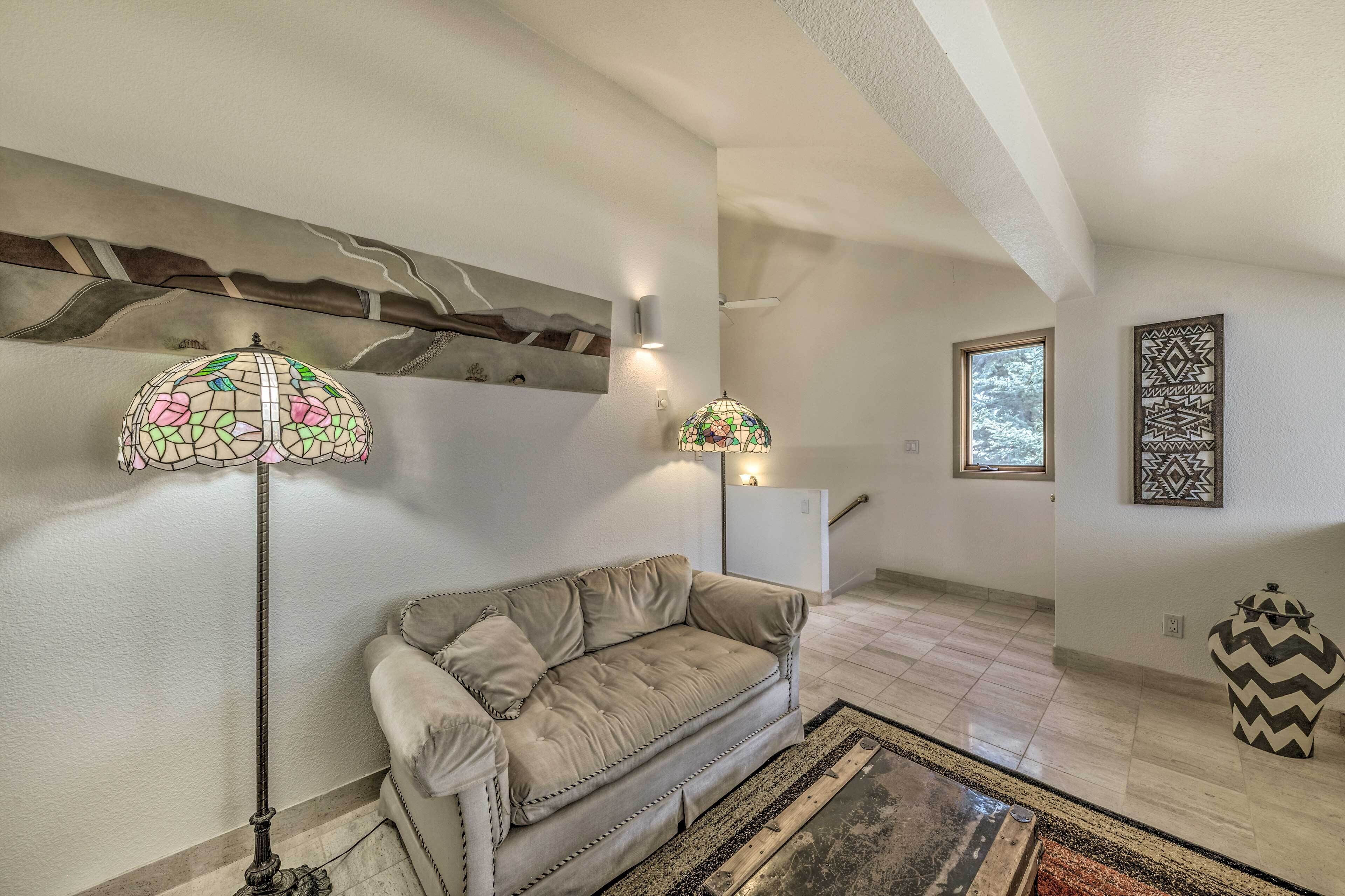 A living room with a beige sofa, a patterned floor rug, a tall floor lamp, and a decorative wall piece.