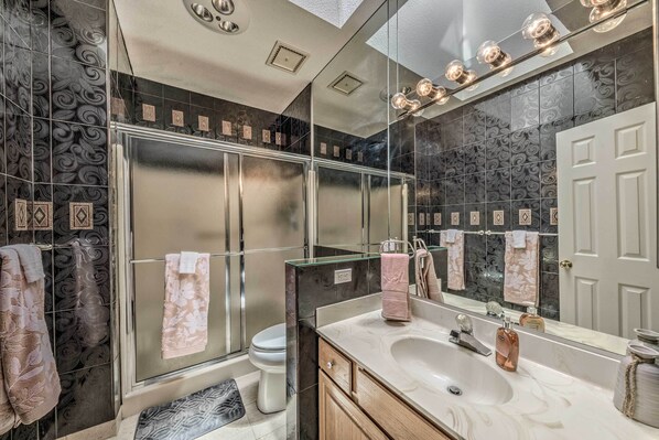A modern bathroom with a glass shower enclosure, a large mirror, and a vanity with a sink.