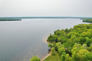 A large body of water with a dock and lush greenery on the shore. - Near Snowmobiling! Carp Lake Cottage w/ Fire Pit (Carp Lake)