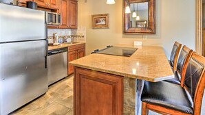 A kitchen with wooden cabinets, a stainless steel refrigerator, a microwave, and a granite countertop. - Copper Mountain Ski-in/ski-out Condo w/ Balcony! (Copper Mountain)