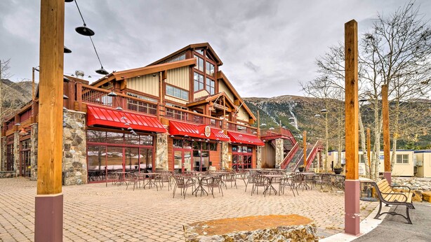 A lodge with a red roof, stone walls, and a patio area with outdoor seating. - Copper Mountain Ski-in/ski-out Condo w/ Balcony! (Copper Mountain)
