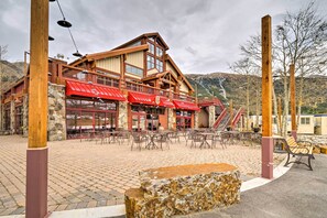 Eine Lodge mit rotem Dach, Steinwänden und einer Terrasse mit Sitzgelegenheiten im Freien.