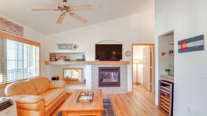 A living room with a sofa, coffee table, fireplace, TV, and ceiling fan. - Condo w/ Mtn View < 1 Mi to Steamboat Resort! (Steamboat Springs)