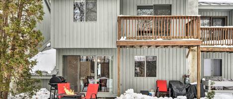 Une maison à deux étages dotée d’une terrasse couverte, d’un barbecue et d’un foyer extérieur.