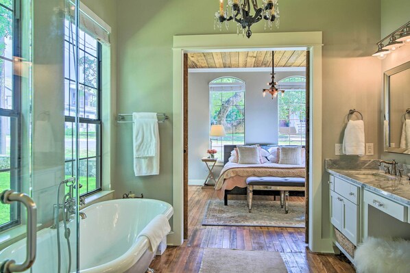 A spacious bathroom with a freestanding bathtub, a large mirror, and a vanity with a sink.