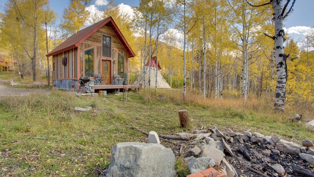 A cabin with a wooden exterior, a porch, and a fire pit area. - Colorful Cabin w/ Teepee, Fire Pits & Mtn Views! (Carbondale)