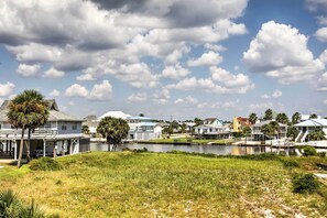 A waterfront property with a covered patio, a small dock, and a grassy area. - Gulf Shores Condo w/ Pool Access: Steps to Beach! (Gulf Shores)