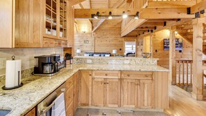 A wooden cabin interior with a kitchen area featuring granite countertops, wooden cabinets, and a built-in stove. - 1 Mi to Slopes! Family-friendly Massanutten Cabin (McGaheysville)