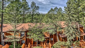 Eine rustikale Lodge mit mehreren Holzhütten, umgeben von dichtem Wald und Bergen im Hintergrund.