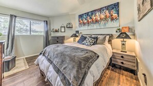 Ein Schlafzimmer mit Bett, Nachttischen, Deckenventilator, einem Fenster mit Vorhängen und einem Gemälde an der Wand.