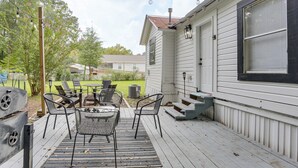 Un porche techado con mobiliario exterior, una parrilla y luces colgantes.