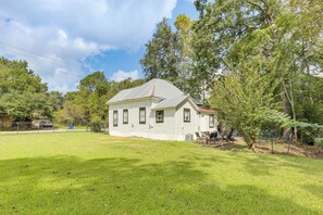 A single-story house with a sloped roof, surrounded by a well-maintained lawn and trees.