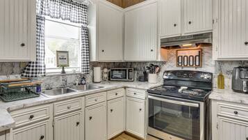 A kitchen with white cabinetry, a microwave, a stove, and a sink.