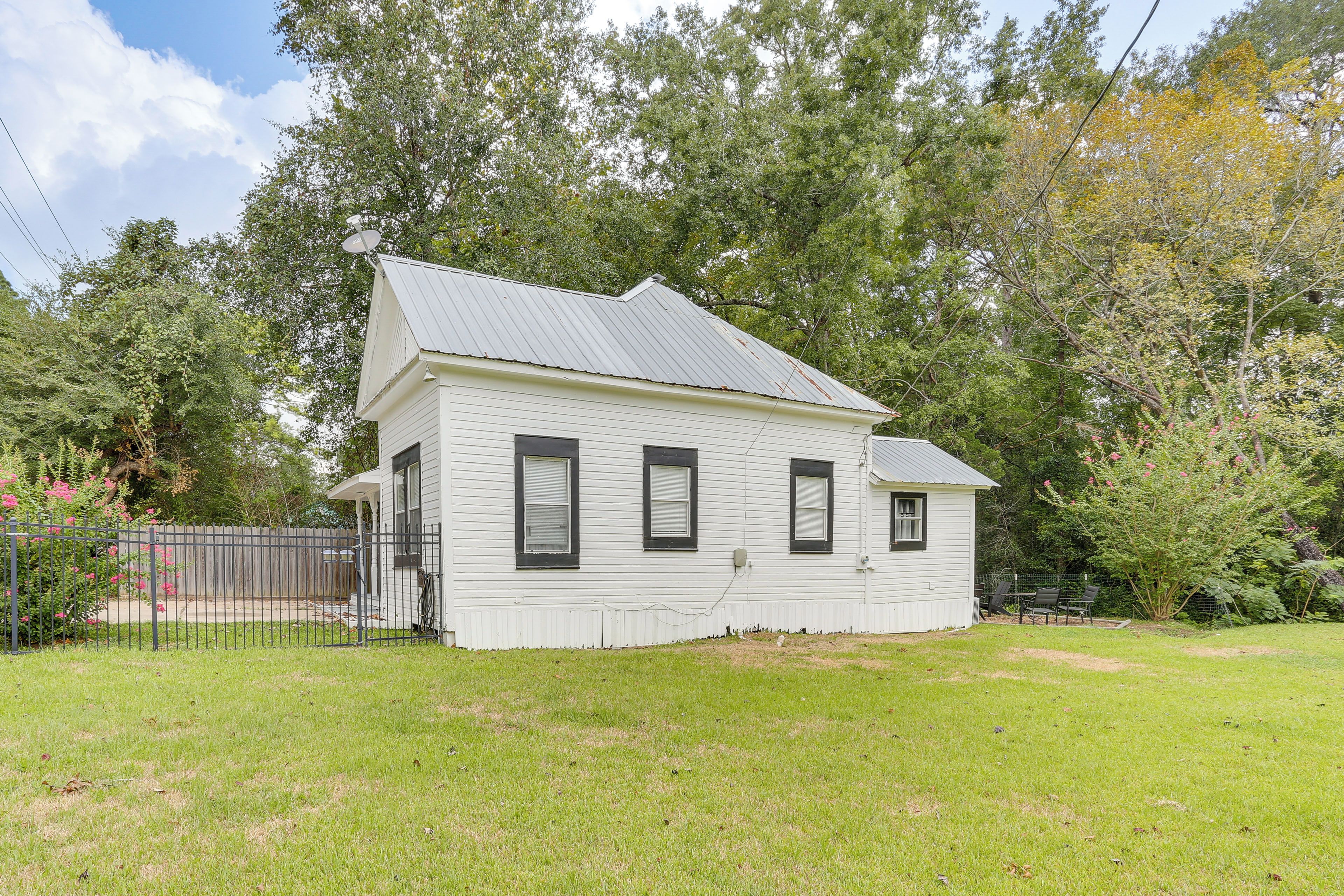 A two-story house with a gabled roof, a front porch, and a fenced yard.