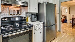 Una cocina con armarios blancos, un refrigerador de acero inoxidable y una estufa negra.