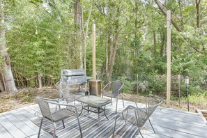 An outdoor deck with metal chairs and a grill, surrounded by trees. - Cozy Livingston House w/ Fenced Yard + Patio! (Livingston)
