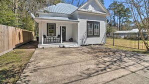 A small, single-story house with a porch, a fenced yard, and a clear sky. - Cozy Livingston House w/ Fenced Yard + Patio! (Livingston)