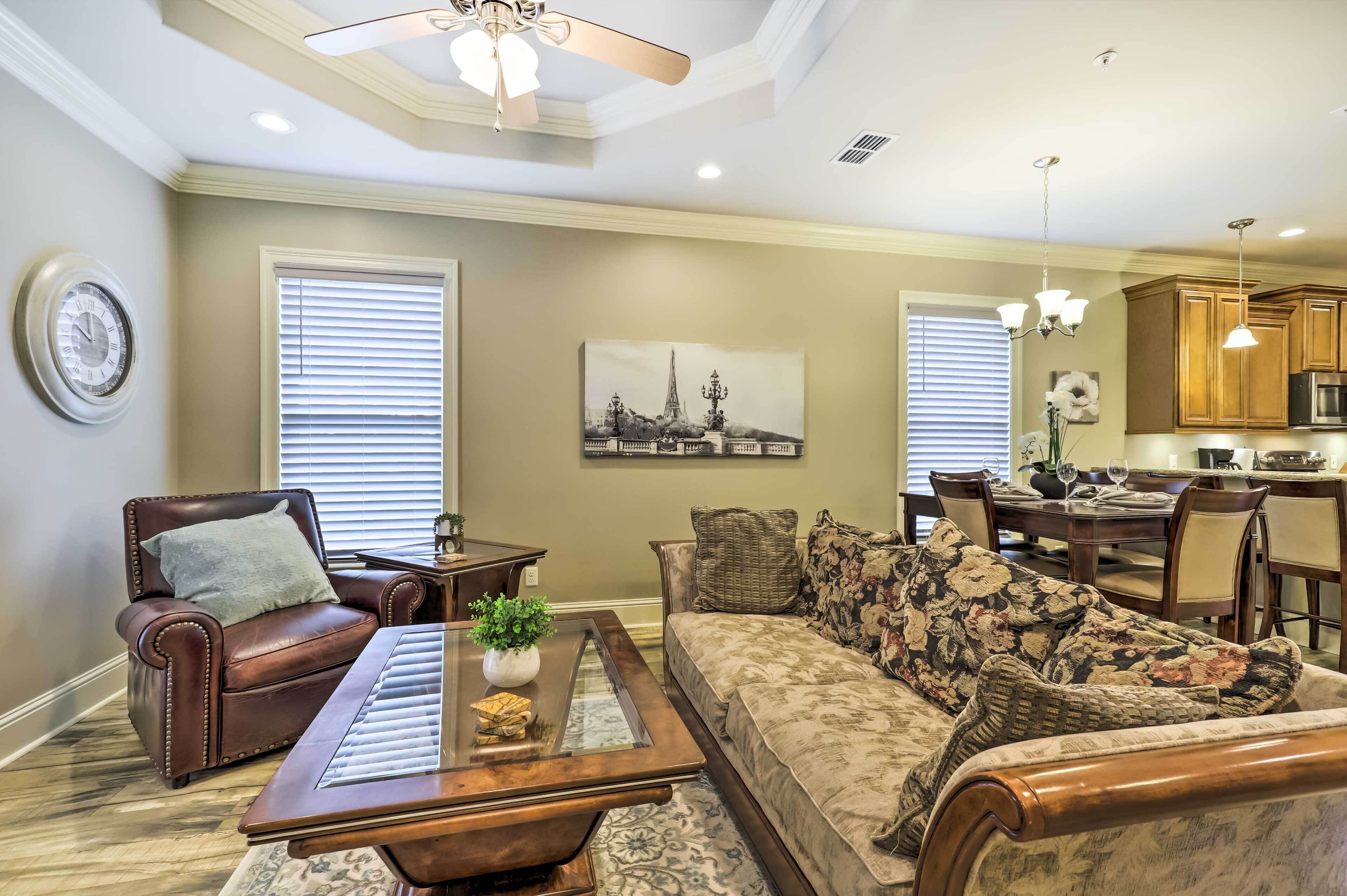 A living room with a brown leather sofa, a wooden coffee table, and a dining area with a wooden table and chairs.