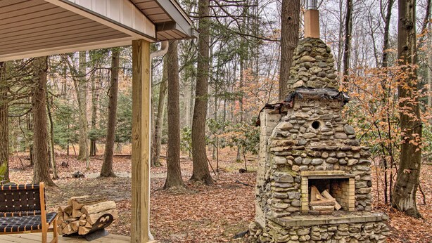 A stone-built fireplace on a wooden deck surrounded by trees.