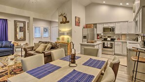 A spacious living area with a dining table, sofas, and a ceiling fan.