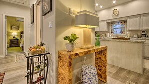 A modern kitchen with a wooden island, a glass table with a fruit basket, and a potted plant.
