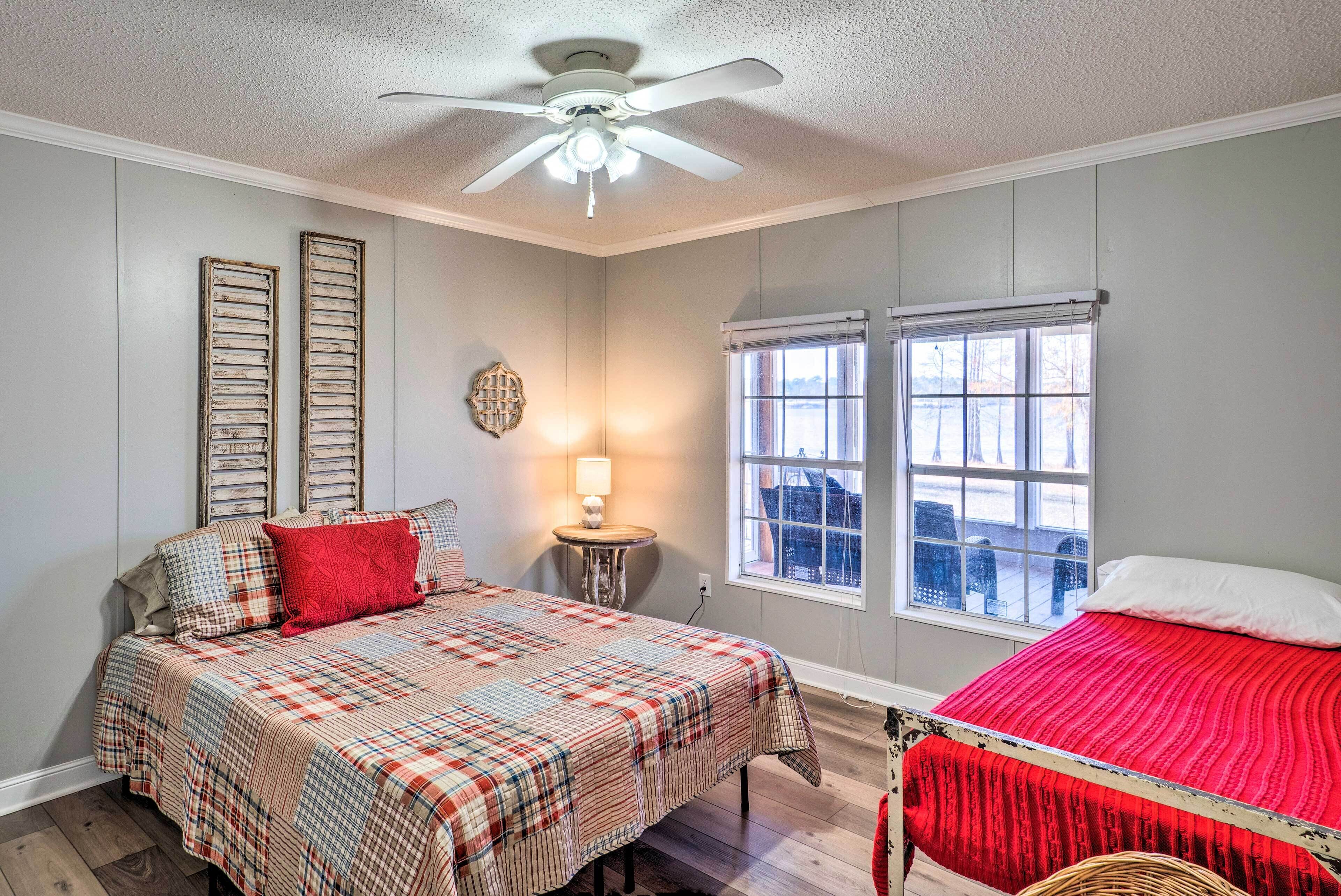 A bedroom with a bed, a window, a ceiling fan, and a nightstand with a lamp.