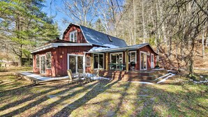 A red wooden cabin with a covered porch and a stone pathway leading to the entrance.