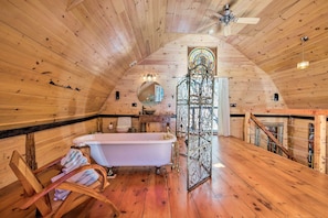 A wooden cabin interior with a bathtub, wooden chair, and a decorative gate. - Cullowhee Getaway w/ Fireplace on Private Meadow (Cullowhee)