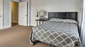 A hotel room with a bed, a nightstand, a lamp, and a door leading to another room. - Dtwn Family Home 2 Mi to Indiana Convention Center (Indianapolis)
