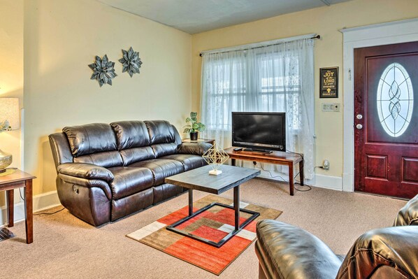 A living room with a leather sofa, a coffee table, a TV, and a door with a glass panel. - Dtwn Family Home 2 Mi to Indiana Convention Center (Indianapolis)