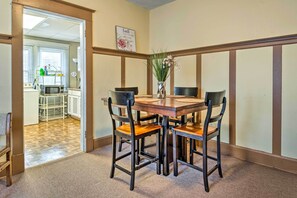 A dining area with a wooden table and four chairs, a vase with flowers, and a kitchen visible through an open door. - Dtwn Family Home 2 Mi to Indiana Convention Center (Indianapolis)