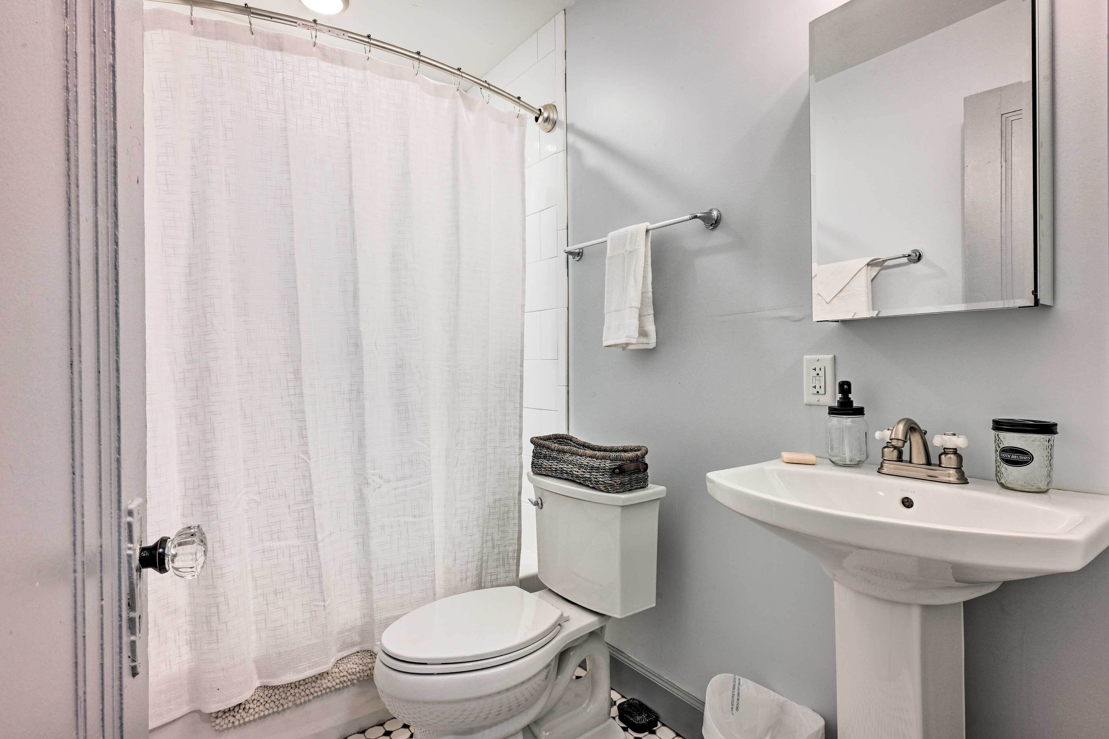 A bathroom with a toilet, a sink, a mirror, and a shower curtain.