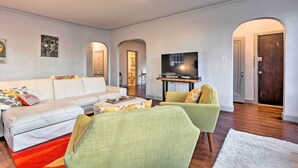 Una sala moderna con sofá, sillones, televisor de pantalla plana y comedor.