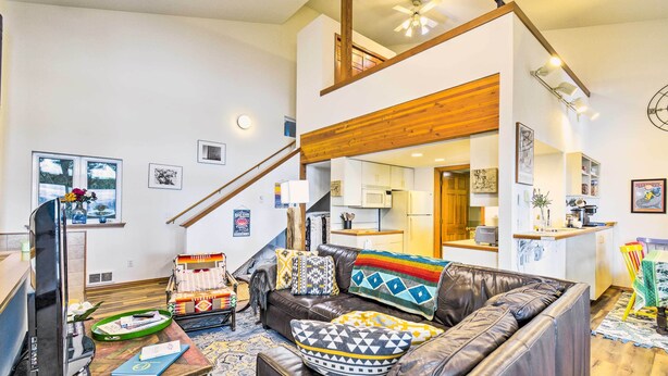 A spacious living room with a brown leather sofa, a television, and a dining area with a wooden table and chairs. - Dreamy Waterfront Studio w/ Hood Canal Views (Shelton)