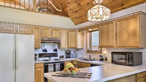 A kitchen with wooden cabinets, a white countertop, a microwave, and a fruit bowl. - Elcho Escape w/ Private Dock on Post Lake! (Elcho)