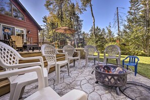 Une terrasse extérieure avec des chaises en plastique blanches, un foyer et une plateforme en bois.