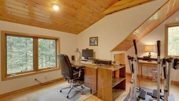 A home office with a desk, chair, computer, and exercise equipment.