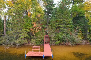A wooden dock extending into a calm body of water, surrounded by dense forest. - Elcho Escape w/ Private Dock on Post Lake! (Elcho)