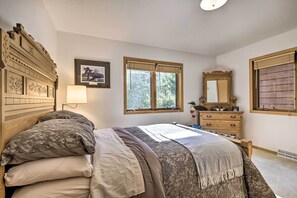 Une chambre à coucher avec un lit, une commode, un miroir et une fenêtre avec des stores.
